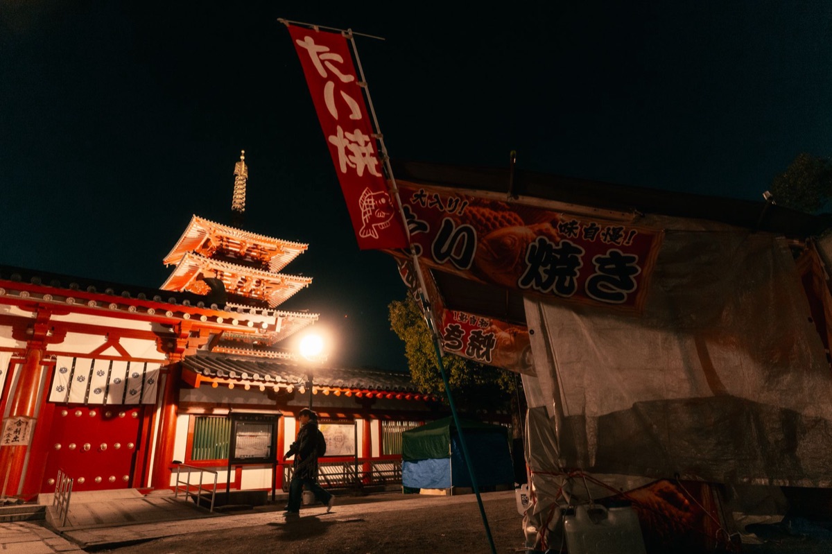 Osaka kushikatsu vendor street with a cart filled with skewers and a customer holding a stick