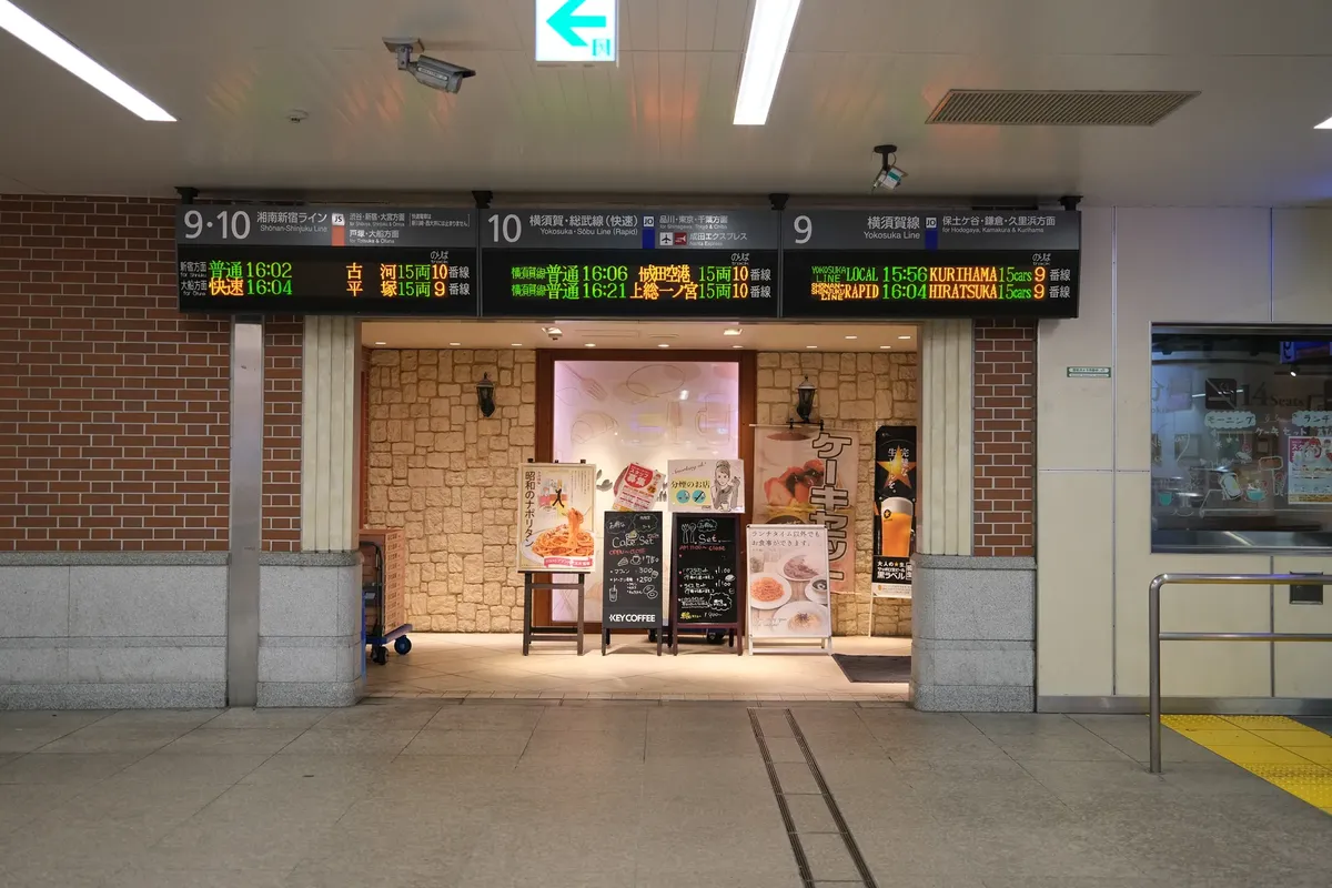 Yokohama Station interior featuring digital train information boards and a cozy restaurant entrance.